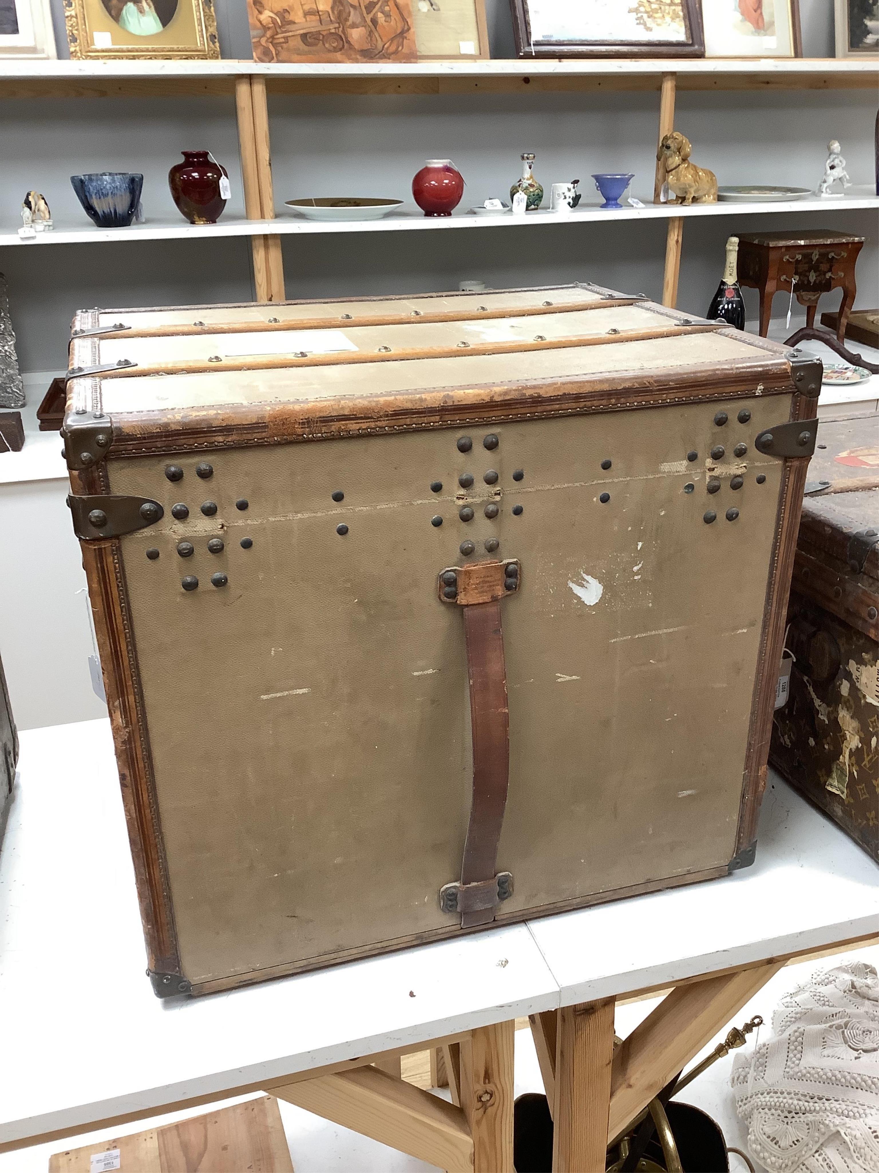 A vintage Louis Vuitton trunk, with brass and leather mounts and studded wooden slats, in plain beige canvas, with label for Paris and London, number 159008, 61cm wide, 48cm deep, 53cm high